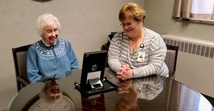 Staff member aids nursing home resident with video call