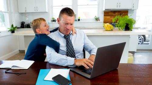 Working_remotely_story.jpg Man working from home with child during quarantine