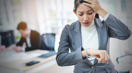 Zoom_Phishing_Hero.png Business woman looking at watch, worried about getting late to meeting