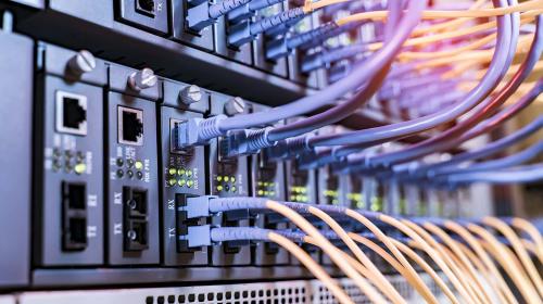 AdobeStock_445362578_1400x933.jpg Server rack with fiber optic cables attached to front panel switch ports