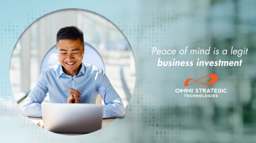 A person sits at a desk using a laptop, appearing joyful. The background features binary code. Text on the right reads, "Peace of mind is a legit business investment," accompanied by the Omni Strategic Technologies logo.